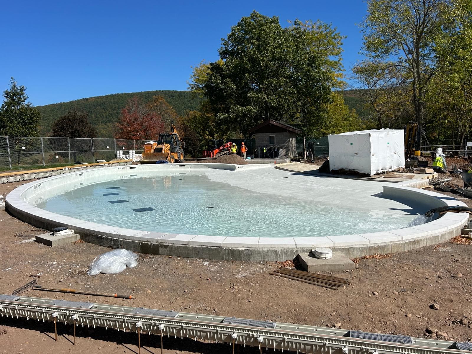 Ground-level view of a circular commercial pool under construction with fresh concrete coping