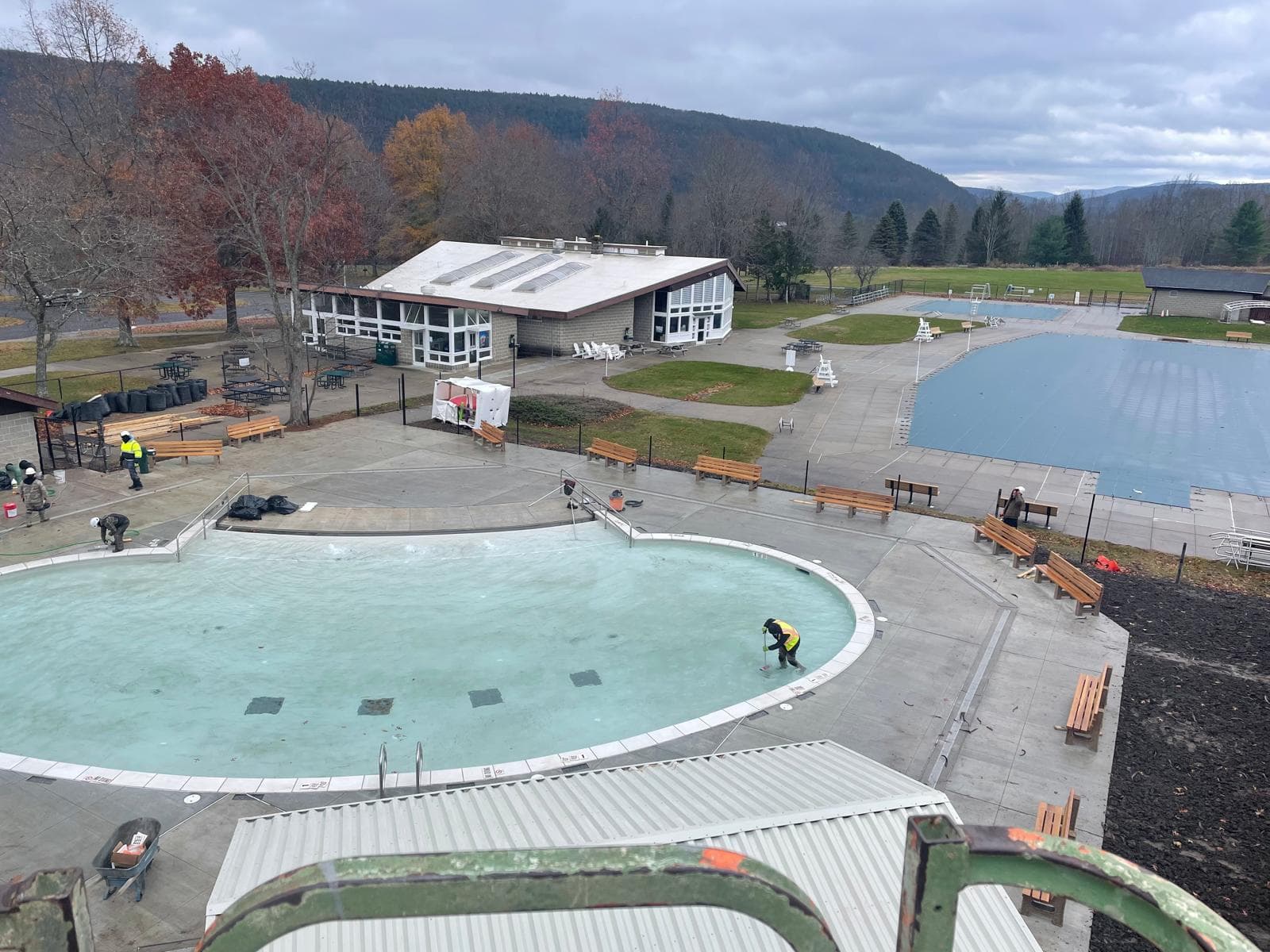 Aerial view of a commercial pool complex with circular and rectangular pools in an autumn mountain valley