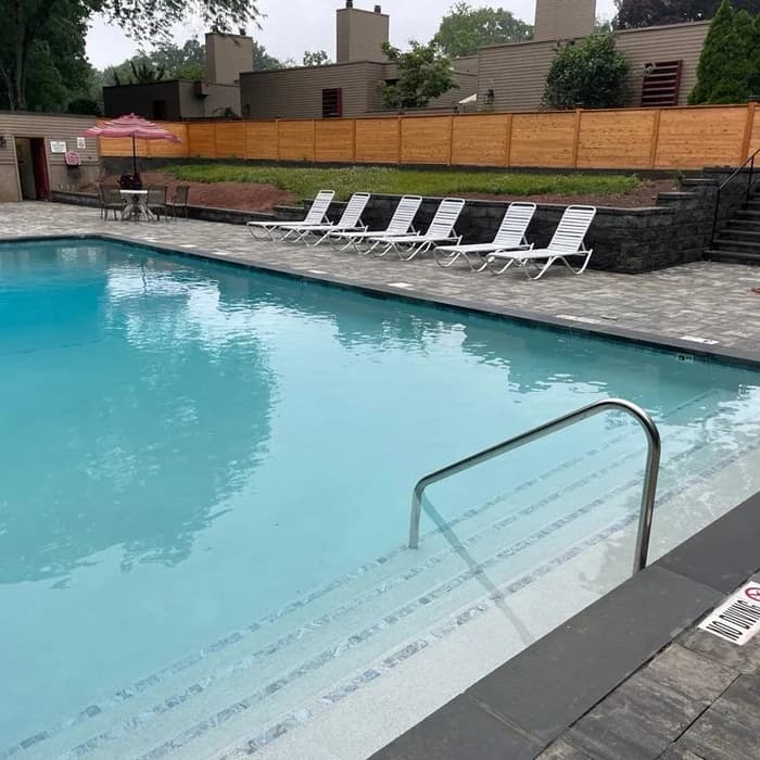 Community pool deck with lounge chairs and wood-fenced perimeter