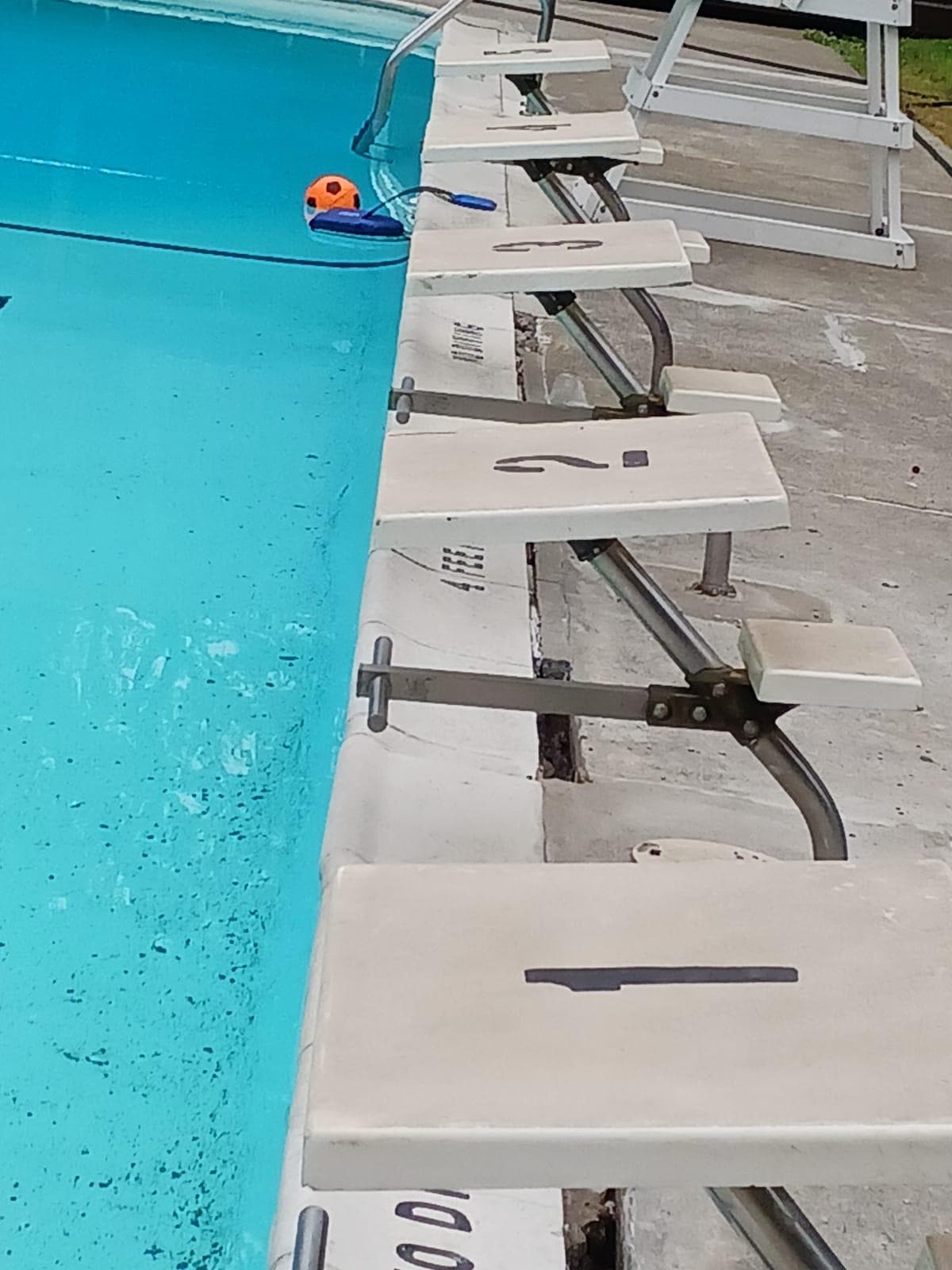 Close-up of numbered starting blocks along the edge of a commercial competition pool