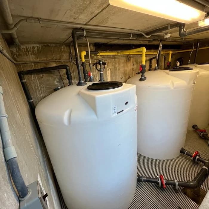 Commercial pool equipment room with feed tanks and filtration plumbing