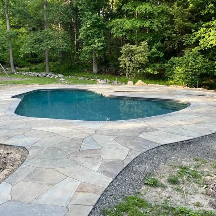 Completed kidney-shaped pool with bluestone patio, the finished luxury result