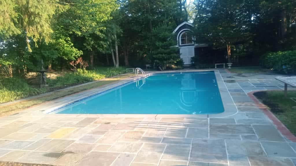 Rectangular pool with flagstone deck and a poolhouse with an arched window