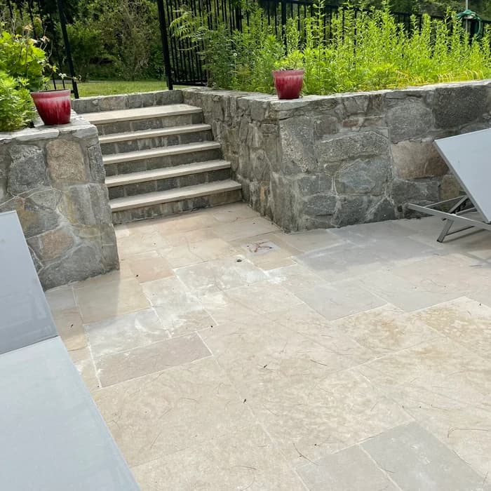 New stone steps and hardscape under construction during pool renovation